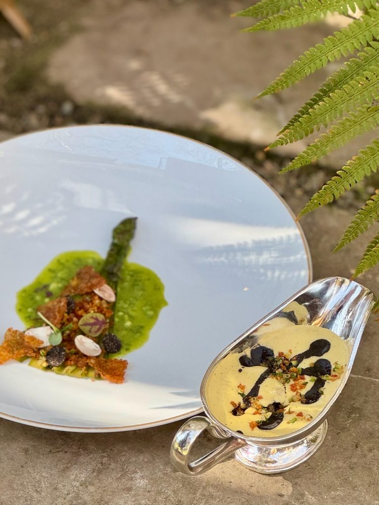 ssiette gastronomique du restaurant 3 étoiles Michelin Michel Guérard : asperge verte étuvée, chapelure de truffe et pomme de terre, accompagnée de sauces raffinées.
