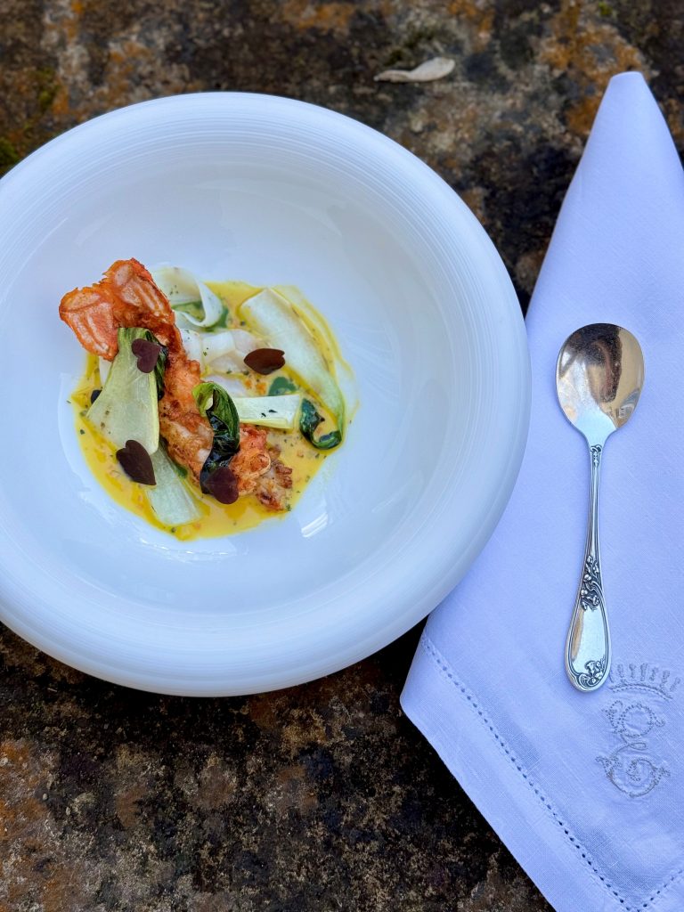 Plat gastronomique du restaurant 3 étoiles Michelin Michel Guérard : langoustine dorée au beurre d’épices, accompagnée de rubans de seiche et d’une sauce onctueuse à base de nage de homard et beurre de mer.